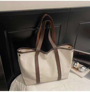 Sac fourre-tout en toile chic avec ordinateur sur un lit blanc pour un look lifestyle