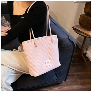Detail of light pink tote bag with vertical textured leather and embossed D logo patch