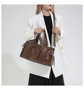 Braune Vintage-Ledertasche getragen an einem Model mit weißem Blazer und schwarzem Rock