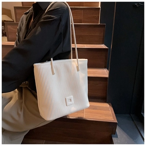 Detailed view of white tote bag featuring unique vertical pleated texture and square decor