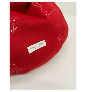 Detail of red wool fabric texture with white floral embroidery and original design tag