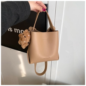 Detail of the litchi grain leather bucket bag with a cute brown plush bear charm