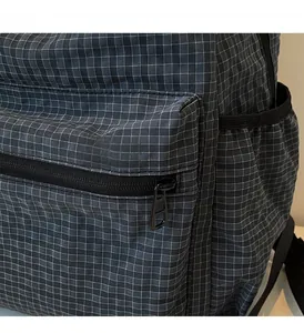 Detail shot of smooth black metal zipper on dark grey plaid fabric of a backpack