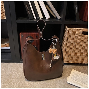 Detail of a large brown hobo bag with silver twist lock and leopard heart pendant