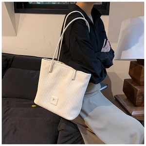 Detailed texture of white pleated tote bag with thin shoulder straps in a modern room
