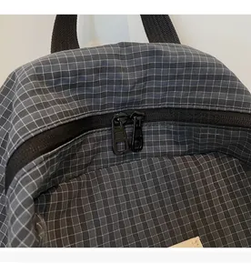 Detail of smooth black metal dual zippers on a gray plaid fabric backpack top
