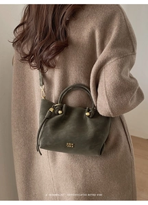 Détail d'un sac seau vintage en cuir vert foncé avec logo doré COIH 2DN élégant