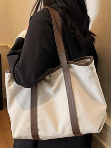 Grand sac cabas en toile beige avec bordure en cuir marron porté à l'épaule pour le quotidien