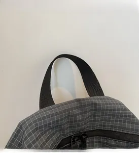 Detail of dark grey grid tear-resistant fabric backpack with black webbing handle and zippers