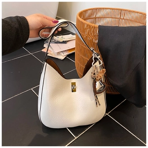 Detail of white hobo bag with gold metal lock and heart leopard print charm