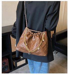 Close-up of brown quilted crossbody bag with gold chain and charming heart star pendants