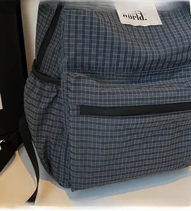Detailed close-up of dark grey-blue checkered nylon fabric and world label on backpack