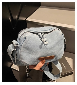 Detail of light blue denim crossbody bag with adjustable strap and vintage texture