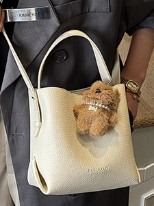 Chic beige lychee leather bucket bag with teddy bear charm and adjustable shoulder strap