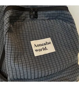 Detail of grid patterned backpack showing double zippers and white brand label logo