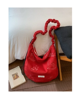Detailed close-up of red tote bag with white floral embroidery and ruched strap