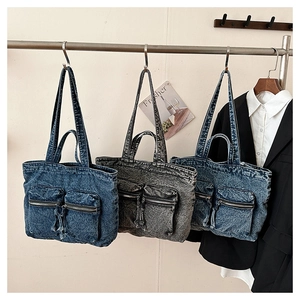 Detail showing various colors of denim tote bags with symmetric zip pockets on metal rack