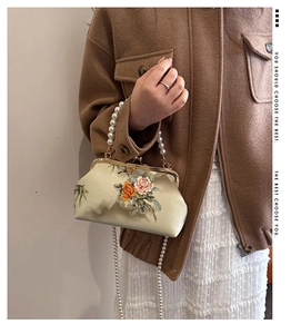 Detailed view of vintage satin kiss-lock bag with floral embroidery and pearl chain handle