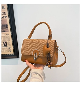 Detail of vintage brown shoulder bag featuring houndstooth flap and metal ring buckle