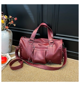 Detailaufnahme einer großen burgunderroten Ledertasche mit Nieten und Reißverschlüssen