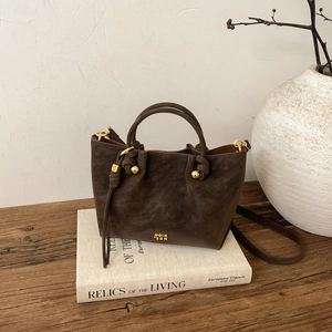 Détail du sac seau café à texture givrée avec des finitions métalliques dorées chic