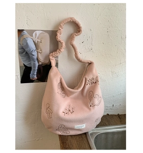 Close-up of pink plush tote bag with cartoon bird embroidery and scrunchie strap