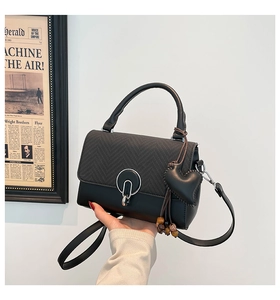 Detailed close-up of retro black crossbody bag featuring heart charm and wooden bead tassel