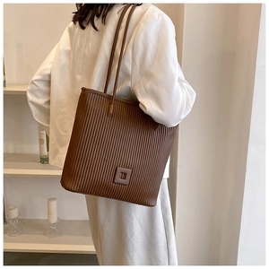 Borsa tote marrone scuro con trama a pieghe verticali indossata da una modella