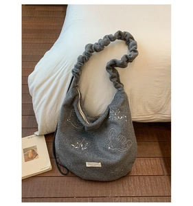 Detail view of dark grey tote with bird embroidery and unique cloud ruffle strap