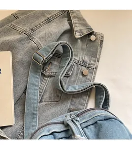 Dettaglio della tracolla regolabile e della cerniera sulla borsa in denim blu