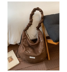 Detailed view of the dark brown tote bag with white embroidery and scrunchie shoulder strap
