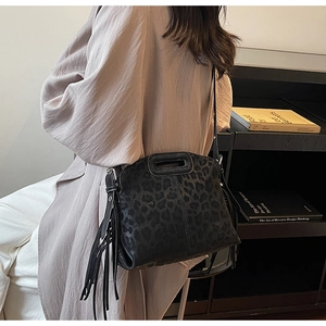 Détail du sac à bandoulière noir léopard avec franges et poignée ovale découpée