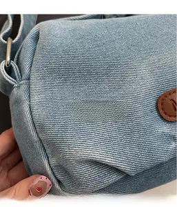 Close-up of light blue denim fabric texture and brown leather patch with embossed letters