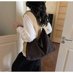 Détail d'un grand sac cabas en daim marron foncé avec relief de croix sur un modèle