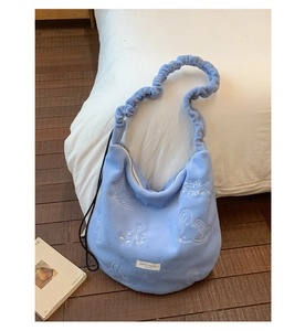 Detailed view of light blue plush shoulder bag with elegant 3D white floral embroidery