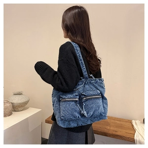 Deep blue washed denim tote bag with two front pockets shown on model in a cozy home setting