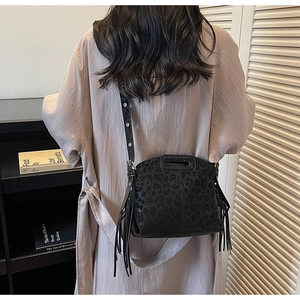 Détail d'un sac bandoulière léopard noir avec de longues franges et une poignée chic