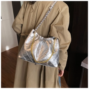 Close-up of metallic silver quilted shoulder bag with dual-tone chain and star charms