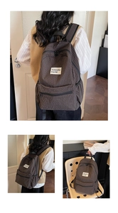 Detail of vintage brown plaid backpack showing fabric texture and front zip pocket