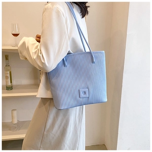 Detail of light blue pleated tote bag with square accent on a stylish shoulder strap