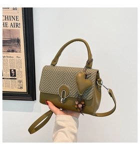 Detail of olive green bag with houndstooth flap, metal ring buckle, and heart pendant