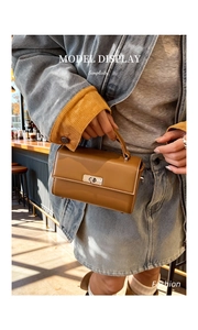Detail of caramel square handbag with silver metal swivel lock worn by model in denim jacket