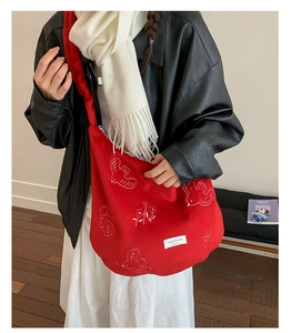 Detail of red hobo bag with white bird embroidery and premium canvas texture