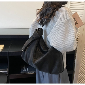 Détail d'un sac cabas en cuir mat noir avec bandoulière nouée sur l'épaule d'un mannequin