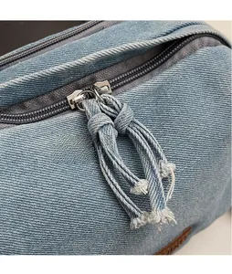 Close-up of denim bag zipper with handmade long knotted denim pullers and frayed edges