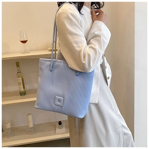 Dettaglio della borsa tote azzurra plissettata con texture e decoro quadrato