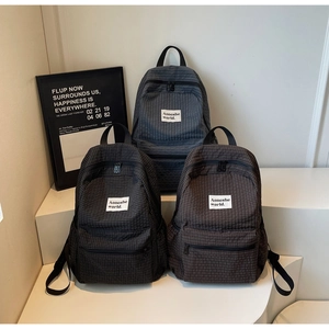 Close-up of lightweight plaid backpacks in black, dark gray and coffee colors with brand label