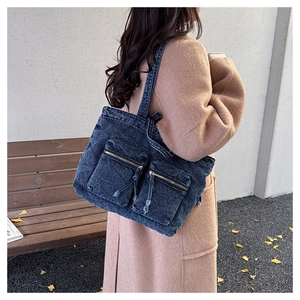 Outdoor shot of a blue washed denim tote bag with large pockets on a wool coat