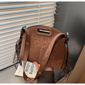 Détail du sac à bandoulière en daim marron avec franges et œillets métalliques