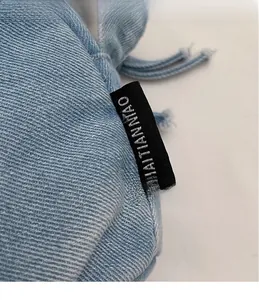 Detailed macro view of denim shoulder bag fabric with a small black rectangular brand label